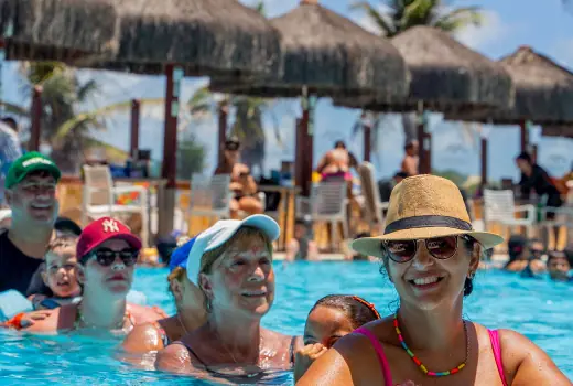 Hóspedes na piscina do Esmeralda Praia Hotel sorrindo para foto e se divertindo muito.