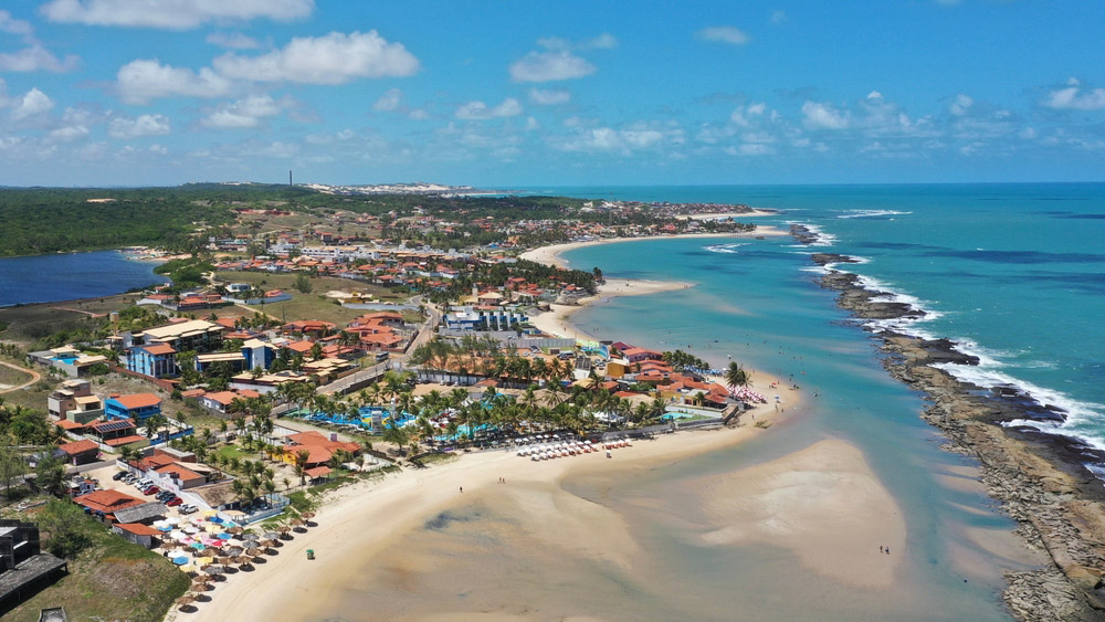 Foto aérea da Praia de Camurupim mostrando o mar, com seus recifes, e uma parte da cidade. 8º posição no Top 10: As melhores praias de Natal-RN e suas proximidades.