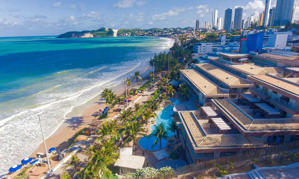 Imagem de drone mostrando o Esmeralda Praia Hotel, à direita inferior da foto, Praia de Ponta Negra à esquerda, e o Morro do Careca ao fundo.