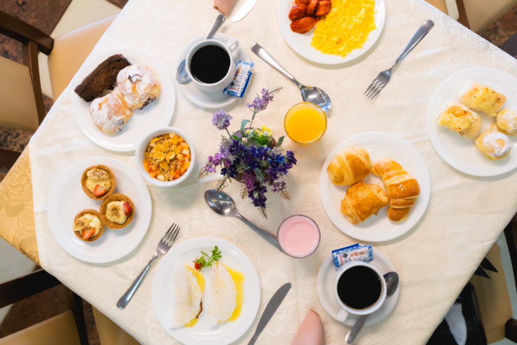 Mesa de café da manhã do Esmeralda Praia Hotel com café, sucos, tapiocas, croissants, pães de queijo e mais.