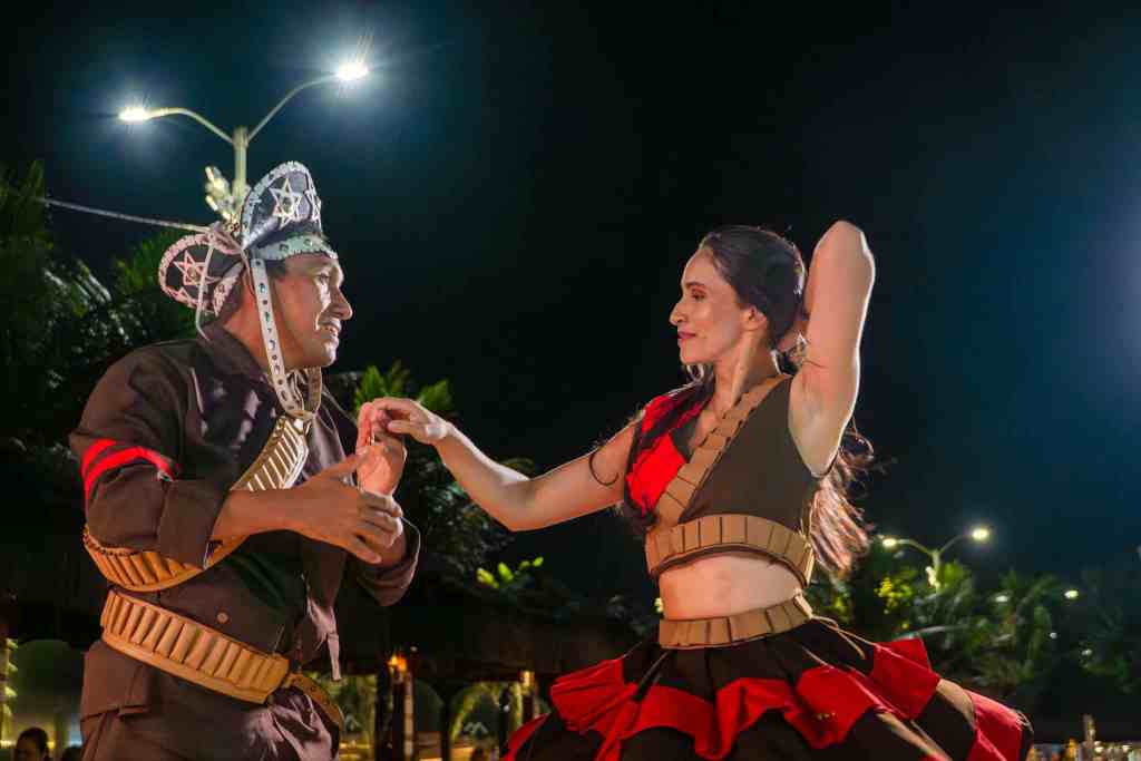 Casal de dançarinos em trajes típicos nordestinos se apresenta na Noite Temática Nordestina do Esmeralda Praia Hotel, em uma dança tradicional com energia e expressão cultural.