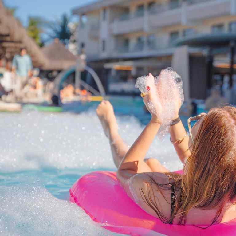 Mulher curtindo espuma em boia inflável na piscina do Esmeralda Praia Hotel, experiência de lazer em Natal Rio Grande do Norte