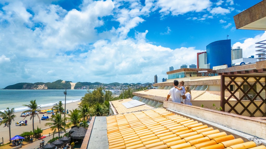 Família na varanda do Esmeralda Praia Hotel, curtindo a vista para o Morro do Careca e a Praia de Ponta Negra.