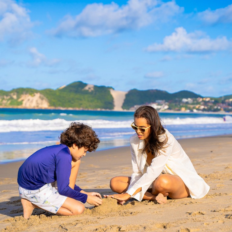 Mãe e criança na areia da Praia de Ponta Negra em Natal.