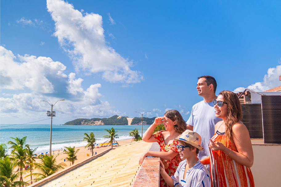 Família apreciando a vista da varanda do quarto do Esmeralda Praia Hotel.