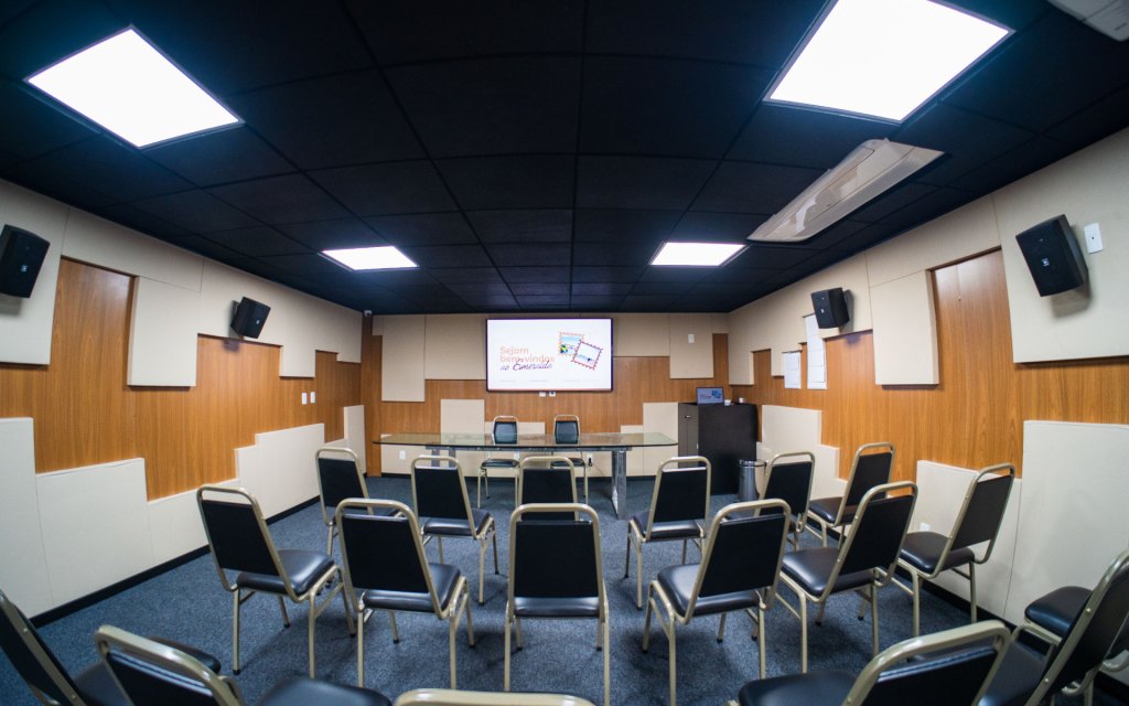 Sala de treinamento do Esmeralda Praia Hotel com telão de boas-vindas e cadeiras auditório