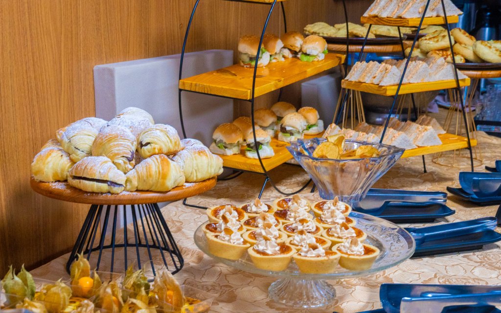 Mesa de coffee break com croissants, mini hambúrgueres, tortinhas e salgados no Esmeralda Praia Hotel