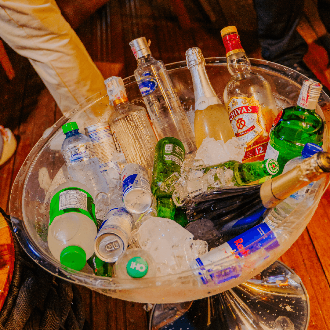 Garçom preparando balde de bebidas com espumante, destilados e água nas mesas do Réveillon Esmeralda